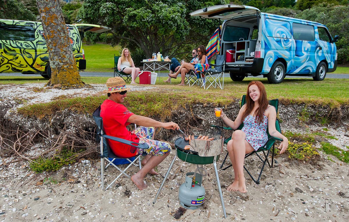 Escape Rentals happy campers next to their campervan at the beach