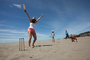 family playing cricket on sumner beach